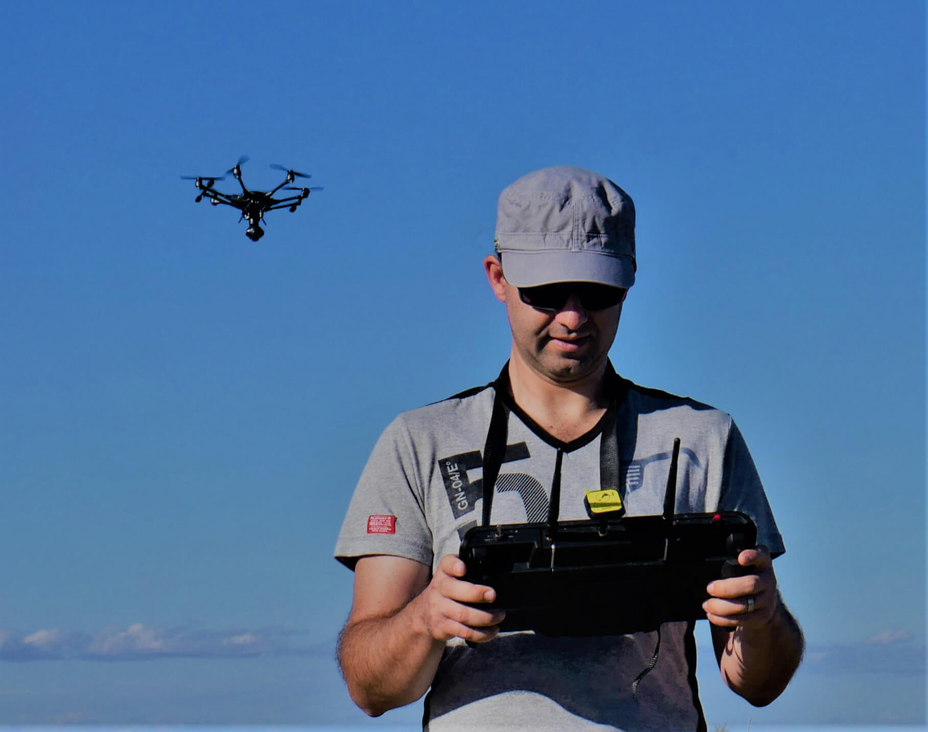 photo du télé pilote Jérémie Pinto avec sa radio commande et un drone en arrière-plan